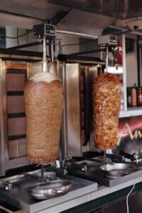 Two rotating meat rotisseries in a professional kitchen, showcasing traditional cooking methods.