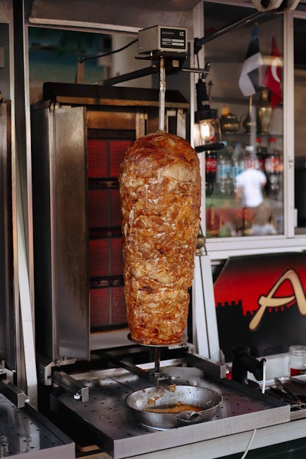 Close-up of succulent shawarma meat roasting on a vertical rotisserie in a restaurant setting.